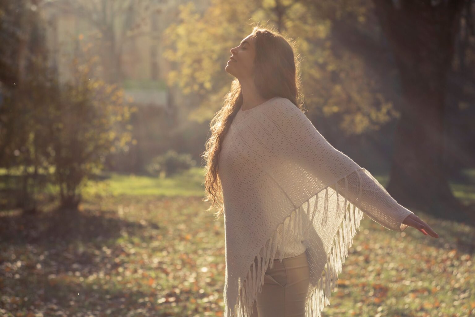 une femme dans la nature les bras ouverts pour illustrer bienfaits de la sophrologie sur l'esprit et le corps