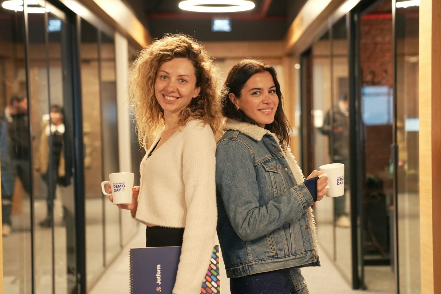cohésion d'équipe : 2 jeunes femmes complices dos à dos avec leurs tasses à café en main