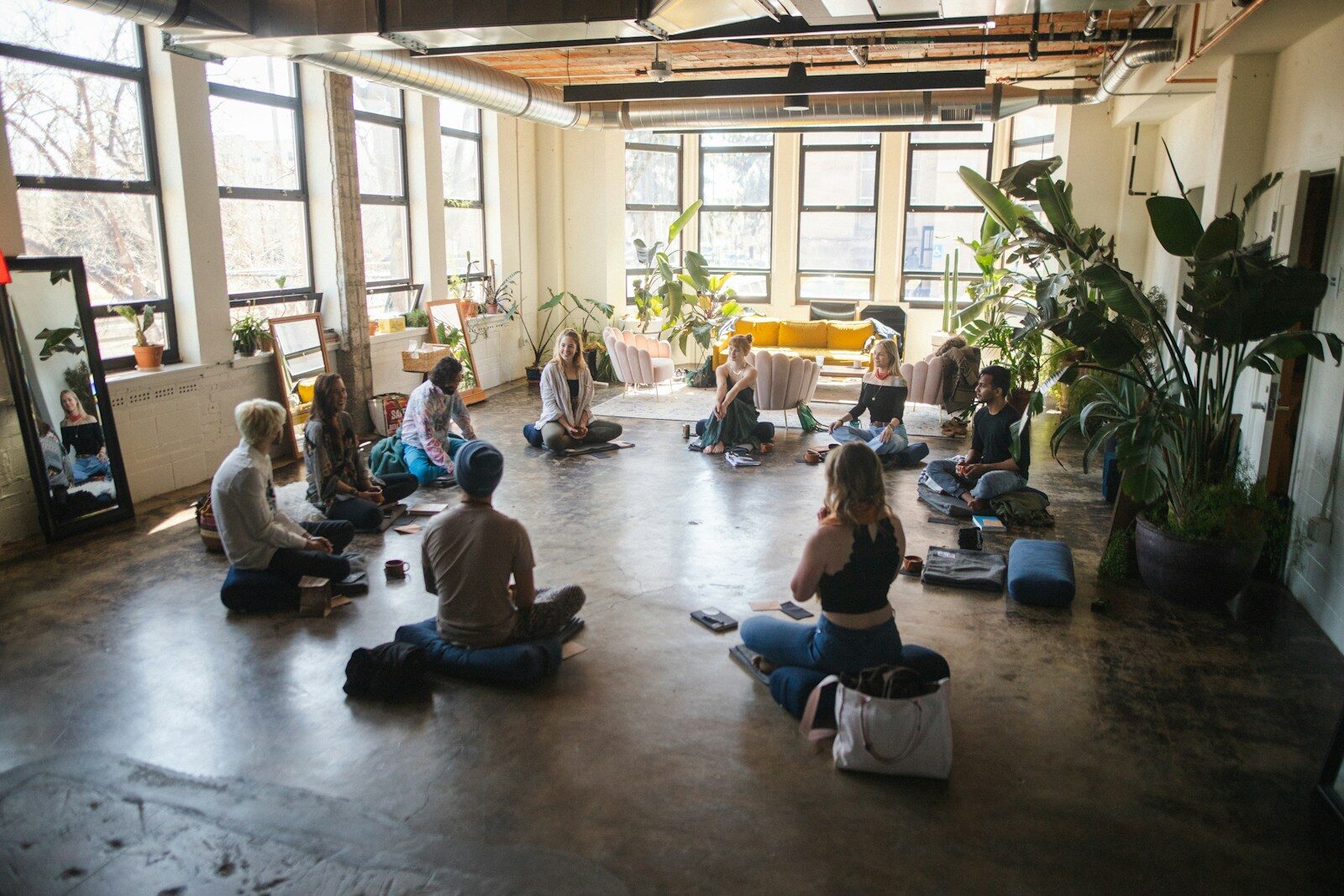 Un groupe de personnes assises en cercle dans une salle lumineuse lors d'une méditation en entreprise